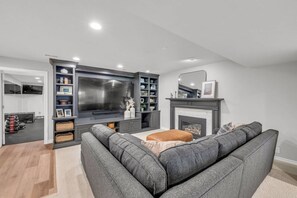 This Family Room with Large Flat Screen TV and a Fireplace is right next to the gym downstairs. Gym area can be closed off.