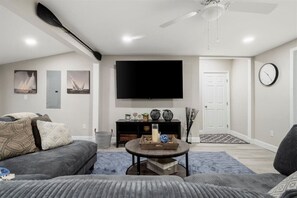 Inviting living space with a huge smart TV and a sumptuous, comfortable couch, offering an ideal setting for entertainment and relaxation
