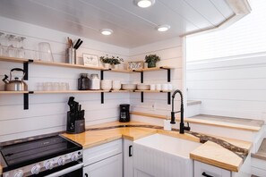 The kitchen is fully equipped with a refrigerator, freezer, microwave, stove and oven, and sink with hot/cold water. Enjoy coffee from the coffee maker, with cookware, dishes, utensils, and plenty of storage cabinets to keep everything organized.