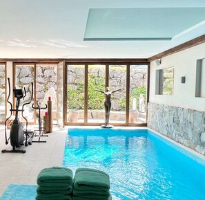 The luxurious indoor pool is equipped with gym equipment.