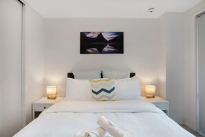 The Queen bed looks cosy and inviting with its bedside tables and soft lighting.