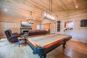 Pool table/game room in living area that opens with barn doors to kitchen
