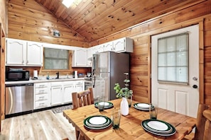 "Effortlessly whip up your favorite meals and entertain guests in style with this fully equipped cabin, where the kitchen seamlessly blends into the cozy living and dining area."