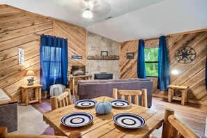 The blue curtains in the living room perfectly complement the hardwood interior, creating a relaxing and visually pleasing atmosphere in the cabin.
