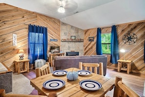 The blue curtains in the living room perfectly complement the hardwood interior, creating a relaxing and visually pleasing atmosphere in the cabin.