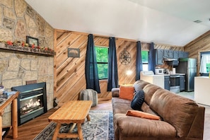 The color scheme inside the cabin is well-balanced and harmonious, with the cozy couch in the living room area perfectly complementing the fireplace.