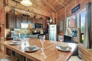 Step into this cozy kitchen with a rustic table and a sleek refrigerator, the perfect setting for creating delicious meals!