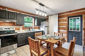 Step into this cozy kitchen complete with a rustic table, comfy chairs, and a sleek stove.