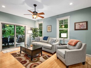 Living room with comfortable seating looks out into scenic back yard.