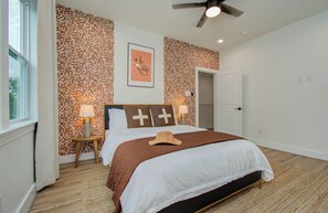 Large queen bed with plush beddings and ceiling fan for the bedroom