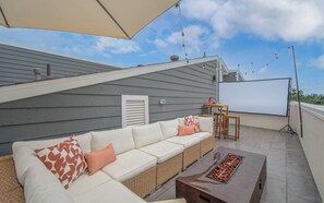 Rooftop patio with cozy lounge, fire table, and outdoor movie projector