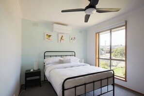 Rest peacefully in the calming primary bedroom featuring a coastal colour palette, tallboy and a queen bed dressed in fresh linen. 
