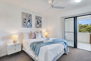 The light and airy primary bedroom includes a queen-size bed with side tables and reading lamps as well as an ensuite.
