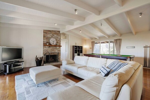 The open-plan living area is the perfect place to settle in with a movie, with a generous corner sofa and a fireplace to keep everyone cosy. 
