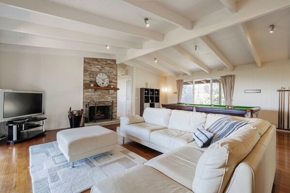 The open-plan living area is the perfect place to settle in with a movie, with a generous corner sofa and a fireplace to keep everyone cosy. 
