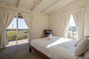 The light and airy primary bedroom offers a queen-size bed and views overlooking the deck.