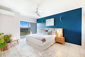 The luxurious primary bedroom includes a king-size bed with floor-to-ceiling views and direct balcony access, as well as a walk-in robe and an ensuite. 
