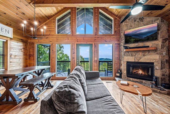 The cabin has large windows that showcase the mountain views along with a door for back patio access.