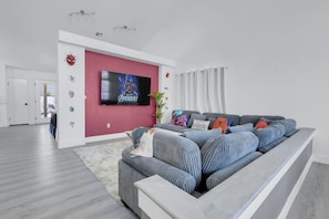 Cozy superhero-themed living room with comfy couches, high ceiling and 75" TV