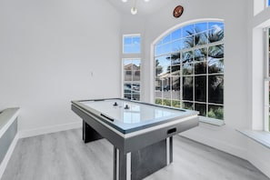 Air hockey table in bright game room with large windows providing natural light