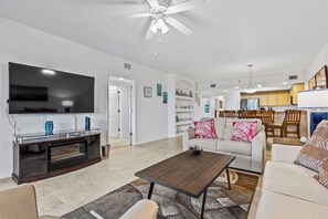 Looking in from the balcony. The spacious living room invites you to relax with cozy seating, a large smart TV, and sliders that open to the balcony.