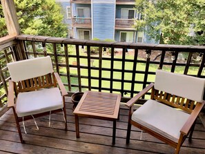 A cozy wooden balcony with two chairs overlooking the pool and courtyard.