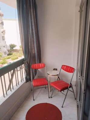  Enjoy the view from the Gadou Rooms' balcony, where two charming red chairs invite you to unwind in a tranquil escape.

