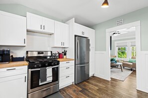 This stunning kitchen radiates a sense of refined elegance and modern functionality. The crisp, white cabinetry creates a clean, airy atmosphere, while the sleek stainless steel appliances and warm wood-toned countertops seamlessly blend form and function.