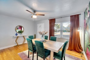 A vibrant, funky dining room with unique wallpaper, a lively grass wall, and a fun lighted sign