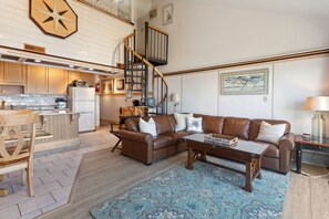 The open-concept Main Level boasts a cozy Living Area with high ceilings, a large Flat Screen TV, and a wall with windows and glass sliders overlooking the Pamlico Sound!