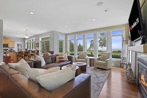 Open concept main level boasting floor to ceiling windows along the lakeside, luxury furniture and gas fire place.