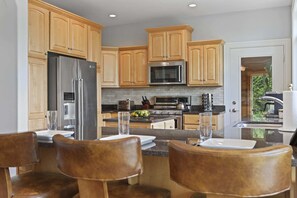 Fully stocked kitchen with island barstool seating, walkout access to the patio and porch, and luxury appliances.