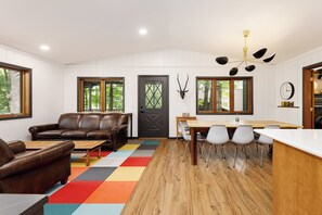 This getaway is the epitome of comfort and charm! With its cozy leather seating, vibrant rug, and serene views from large windows, it's perfect for relaxation and dining with loved ones.