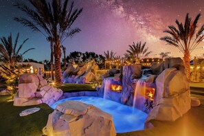 Stunning twilight shot highlights the cascading waterfalls and illuminated pool features.