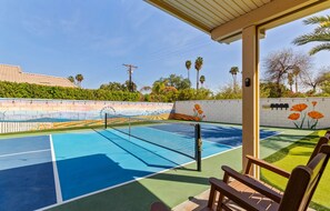 Full-sized pickleball court surrounded by palm trees and private patio seating.