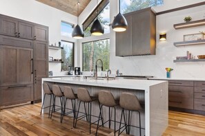 The stylish kitchen is perfect for cooking for a crowd with large marble countertops, luxury grade appliances, two dishwashers, and a large kitchen island.