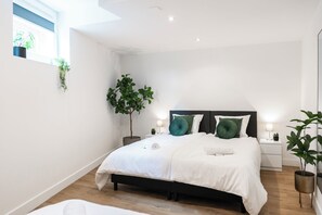 A minimalist bedroom with a soft and inviting bed, plants, and clean lines, providing a tranquil and serene atmosphere.