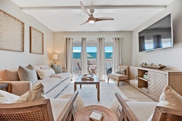 Living area with sleeper sofa, smartTV and balcony access.