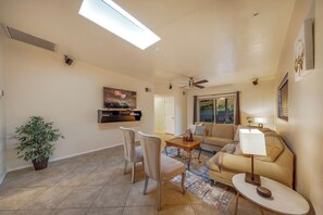 Bright, open living room area with natural light, cozy seating, and smart TV