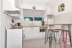 The fully-equipped kitchen features an Expresso Pod coffee machine with a milk frother, microwave, fridge, gas stovetop, and oven. 