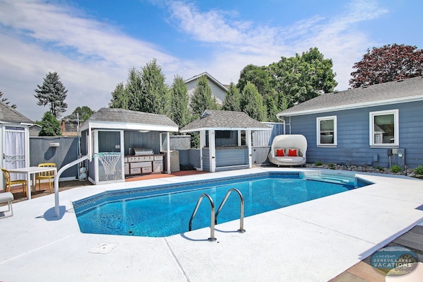 Heated saltwater pool with basketball hoop, outdoor kitchen, and seating