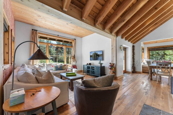 Living room: L-shaped couch, Samsung Smart TV, wood-burning fireplace, open to dining and kitchen