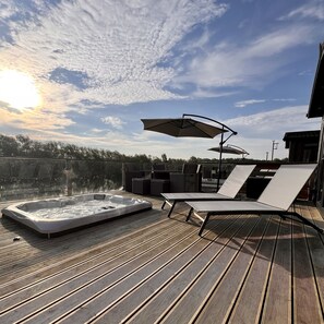 A large lakeside deck offers the perfect outdoor retreat. Immerse yourself in the serene ambience with a bubbling hot tub, a cosy alfresco dining area, & sun loungers shaded by a parasol.
