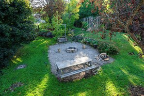 The spacious backyard featuring a fire pit and picnic area, ideal for outdoor gatherings and enjoying the natural beauty.