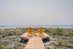 Welcome to Lands End: The cozy seating area features two vibrant yellow chairs facing the stunning views of Lake Huron, perfect for enjoying sunsets or a peaceful morning coffee.