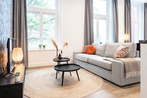 Spacious and stylish studio apartment in Tilburg with a bold patterned wall, comfortable furnishings, and a dining table adorned with colorful floral decor. Perfect for Bed en Koffie near Tilburg Centrum, and an affordable option for Efteling or Safaripark Beeksebergen stays.