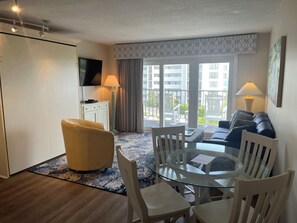 Bright, airy small living space with cozy furnishings and a queen murphy bed