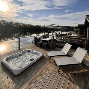 A large lakeside deck offers the perfect outdoor retreat. Immerse yourself in the serene ambience with a bubbling hot tub, a cosy alfresco dining area, & sun loungers shaded by a parasol. Enjoy the views of the brave water ski jumpers as you unwind.