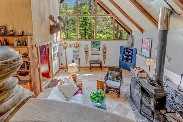 Living Room: Wood-burning fireplace, TV, couch, 2 chairs, soaring windows