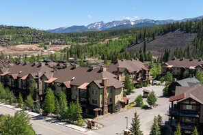 Aerial view of lodge-style condos surrounded by evergreens and mountain ridgelines.